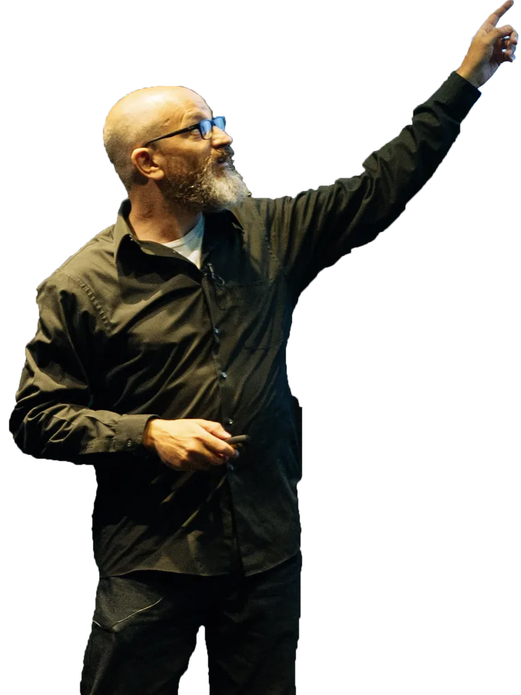 Dr Nick Fine on stage in a black shirt and glasses, in profile, holding a presentation clicker in one hand and pointing up and away with the other